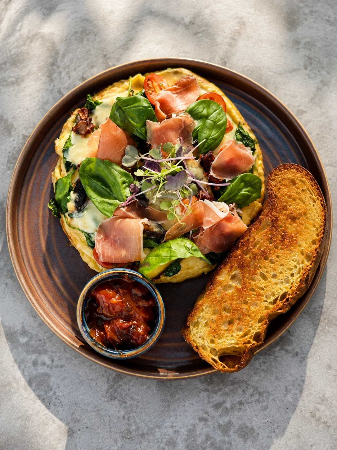 Brunch plate with greens, prosciutto, jam and toast at Eddie's